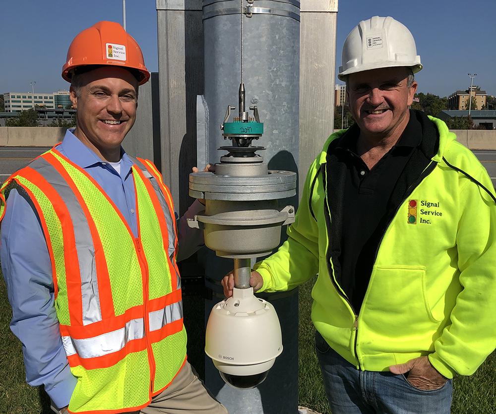 Ryan Brown, president, Signal Service, (left), and Steve Dowdall, ITS director, Signal Service with the MG2 CAT6a Ethernet Camera Lowering Device and a Bosch Starlight IP camera
