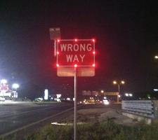 An illuminated wrong way sign in San Antonio at night