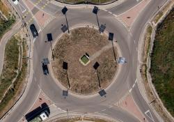 The lamp poles - which are casting long black shadows - are located only on the roundabout island and at a bicycle crossing
